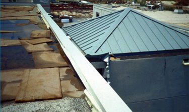 Photo of a metal roof over a stair tower where the irregularity created by the stair tower caused turbulence that resulted in wind speed-up