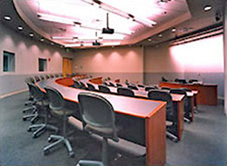 AV equipped classroom with stadium-style setup featuring curved tables and office chairs