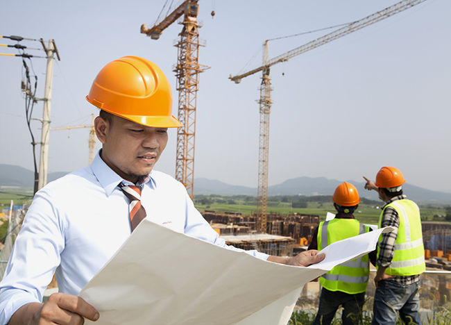 stock photo of worker in a hardhat reviewing construction docments on a work site