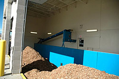 Photo showing piles of wood chips in the wood chip storage area at the Boulder County Parks and Open Space campus district heating system