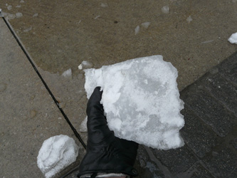 A gloved hand holding a chunk of fallen ice