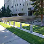 Plain concrete style bollards mounded on a contrete strip placed in the grass between the sidewalk and federal building
