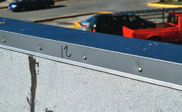 Use of exposed fasteners to attach vertical flanges of coping and edge flashing
