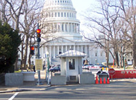 In front of the US Capitol building the guard house is shown next to a red stoplight with concrete planters (without plants) and pre-cast concrete drainage structure rings as barrier protection