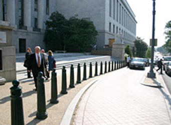 A line of bollards separating a pedestrian sidewalk with a drop-off area and the roadway