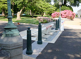 Rising plate vehicle barriers in the center flanked by decorative bollards