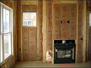 room under construction showing figerglass insulation with brown paper covering in the wall joists