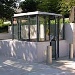 a customed designed guard booth encased with concrete with bollards to the right of it