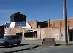 View of a brick building from the back parking lot with a Pepsi logo painted on the side of the building and a highly visible solar panel system on the roof