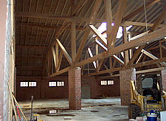 Interiour view of a building the in process of being converted showing the original brick columns, wooden trusses, and skylight