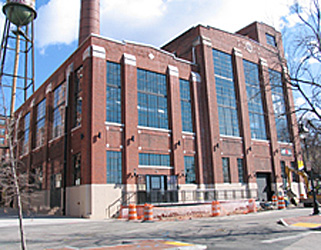 Exterior of a historic red brick building, a former power plant converted to office space, with very large windows that were retained during the converstion