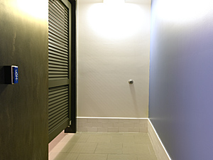 men's bathroom stall with push button door opener and blue wall