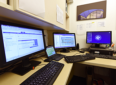 four computer screens engineer uses to monitor building systems