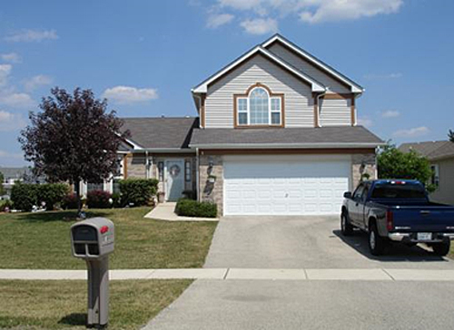 photo of a home with a large single garage door and path from the driveway to the front door