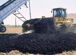Tractor moving biosolids in field