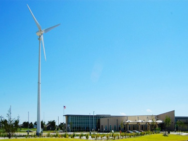 Photo of a distant building with a large wind turbine near to it