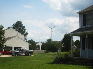 Photo of two residential homes with a wind turbine in the distance between them